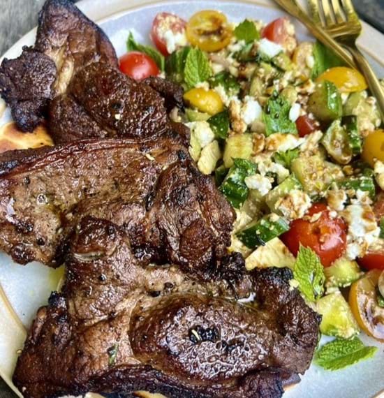 Mediterranean Garlic and Thyme Lamb with a Mint and Feta Salad Mediterranean garlic lamb served with feta salad on a white plate.